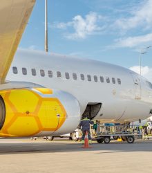 Man baggage handler controlling luggage loading while standing near passenger airplane at airfield