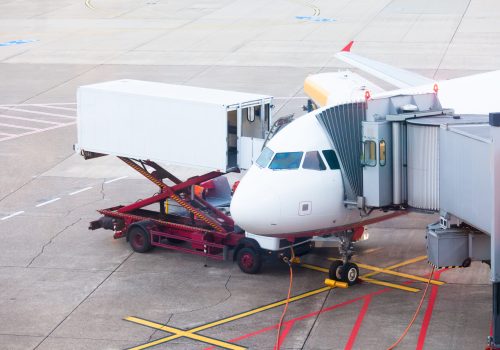 Airliner being prepared for boarding and takeoff on airport docked to terminal and serviced